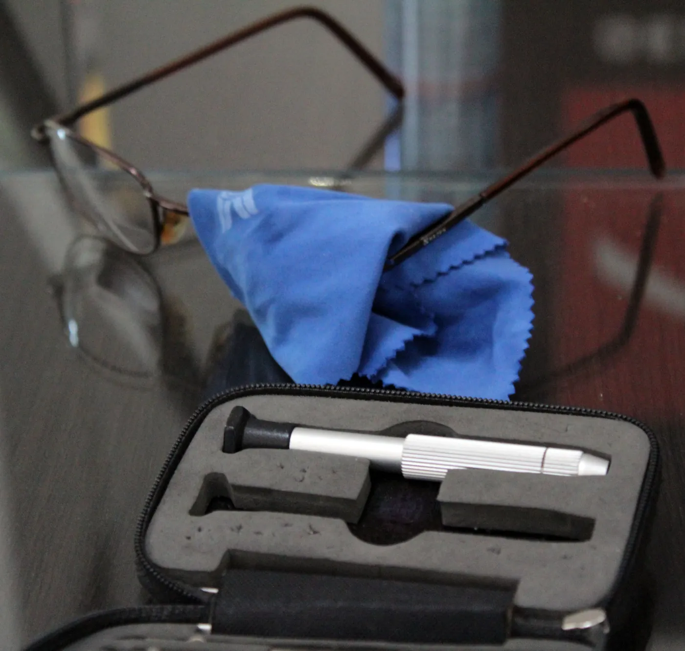 Estuche con desarmador de precisión y paño para lentes junto a unos anteojos