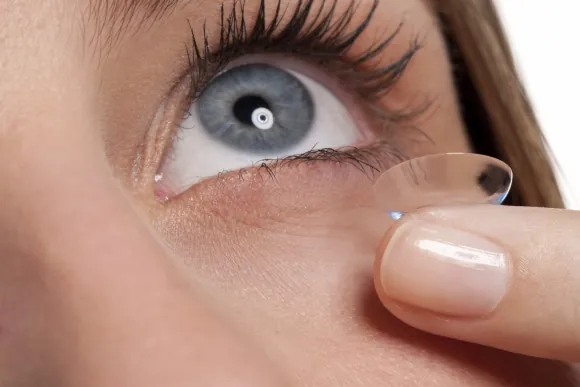 Lente de contacto en la yema del dedo frente a un ojo